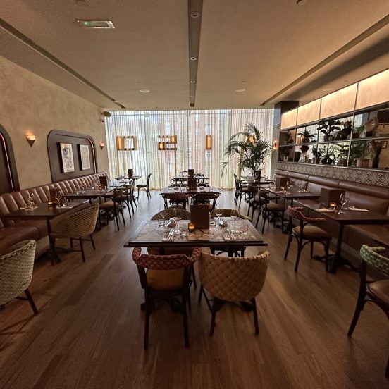 internal view of a restaurant with tables in the middle and banquet seating on the sides.