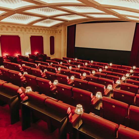 Cinema with red leather couches and plush red carpets. 