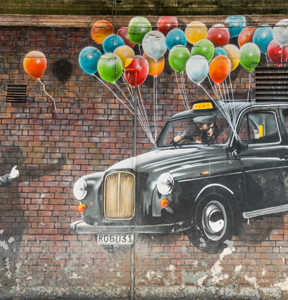 Mural of a man hailing a floating black cab, with colourful balloons tied to its wingmirrors