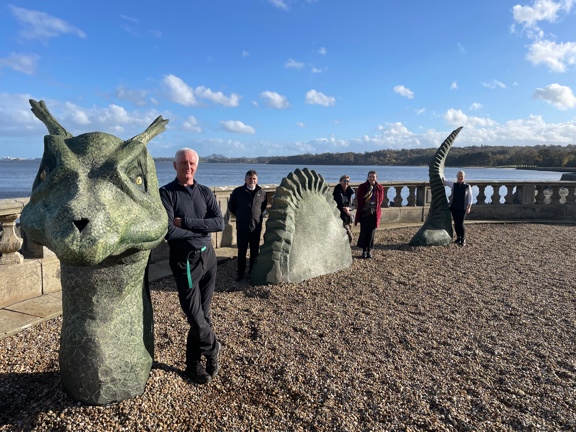 People standing next to a large stone sculpture of a sea monster names Nessie. 