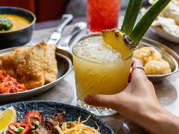 Various Indian food dishes on a table with exotic juice drinks.  