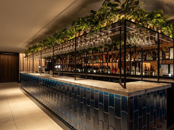 Radisson Blu hotel bar with dark blue tiled front with black mental frame above and wine glasses hanging above.