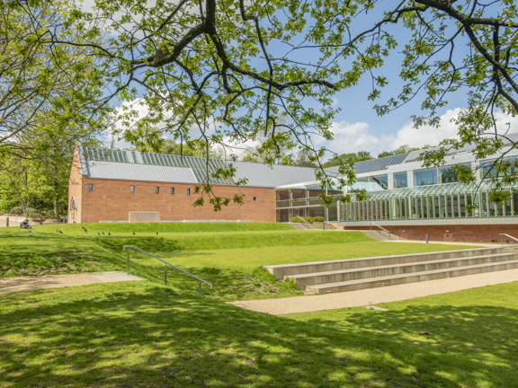 Glass and brick structure of The Burrell Collection through foliage