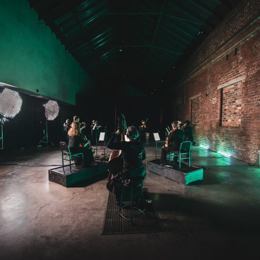 Scottish Ensemble Orchestra in room with brick wall