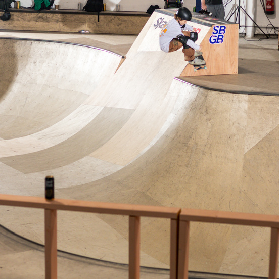 Skateboarder at the top of a ramp with the Visit Glasgow logo in the background