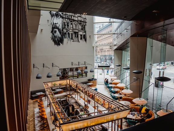 Birdseye view of The Grahamston Bar at Radisson Blu hotel - wooden and marble tiled flooring, floor to ceiling windows, leather and velvet armchairs.