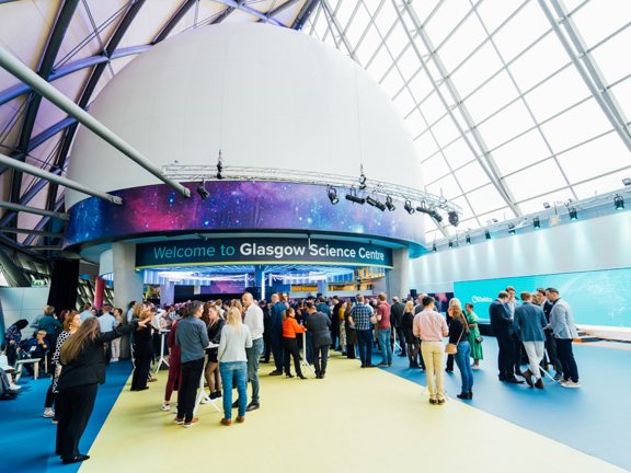 People at a networking event in a modern glass venue called Glasgow Science Centre