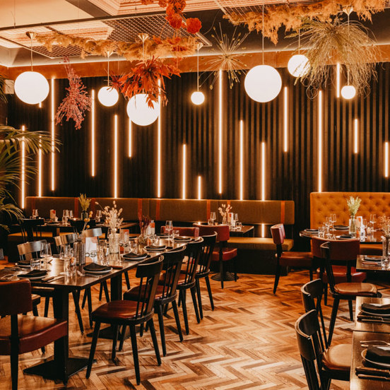 internal view of a restaurant with tables in the middle and banquet seating on the sides.