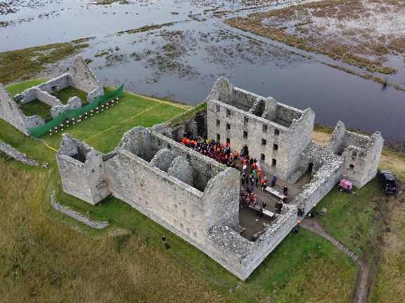 Large group of people gather in the remains of a castle in the Scottish countryside