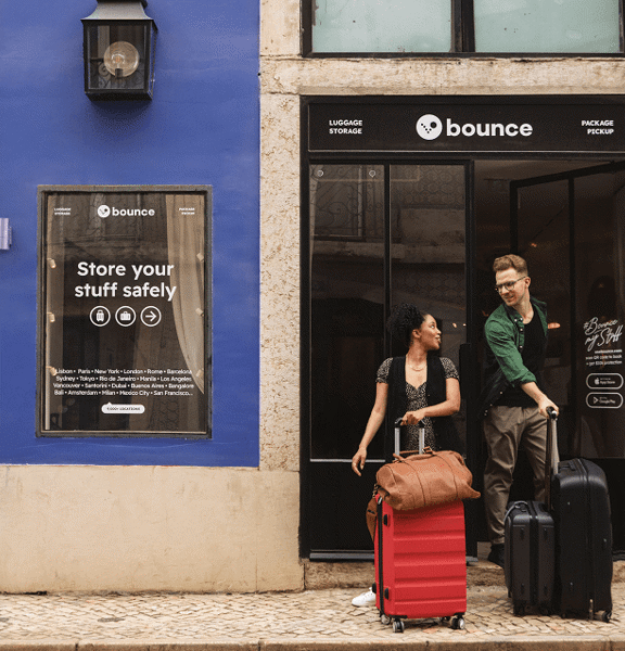 Two people with luggage outside a Bounce luggage storage shop