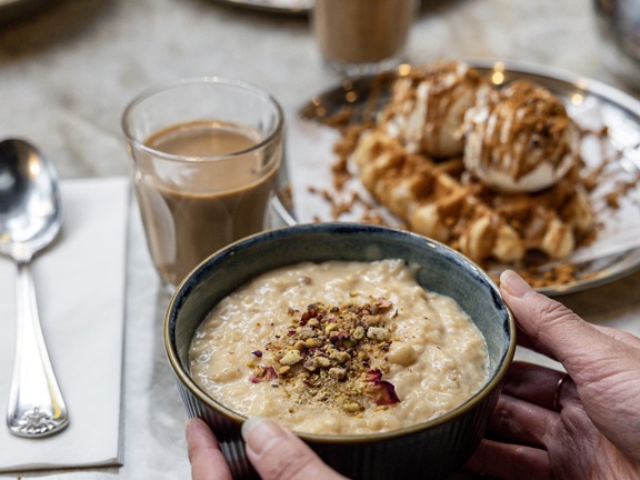 Porridge, chai and waffles dishes on a table.