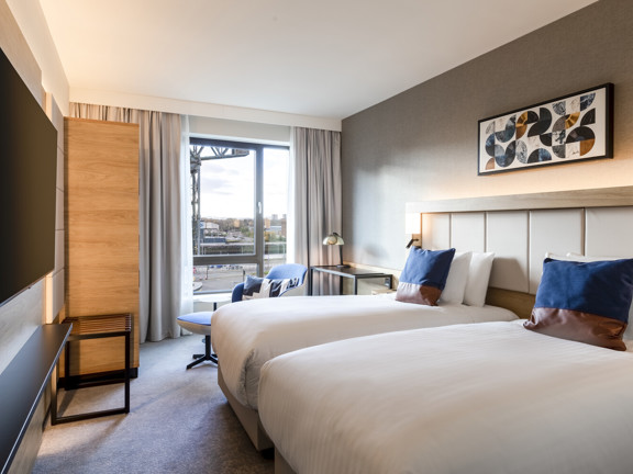 Bedroom with two beds, floor to ceiling windows and view of river.